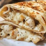 Melted cheesy garlic chicken wraps cut open and stacked, filled with creamy chicken and black pepper. Golden crispy tortillas shine with garlic butter.