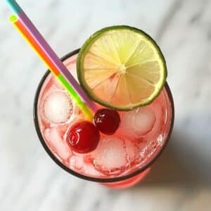 cherry limeades with lime and cherry garnish. Iced and ready to serve on white kitchen counter.