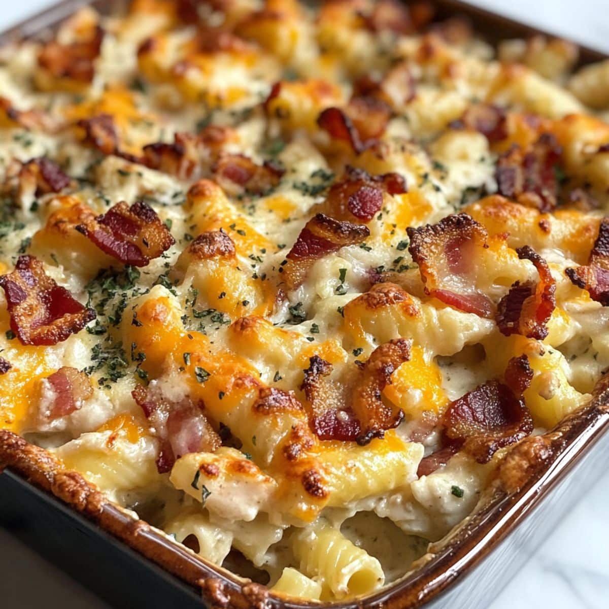 Homemade chicken bacon ranch casserole baked golden in a casserole dish. Crispy bacon and gooey cheese topping on creamy ranch pasta.