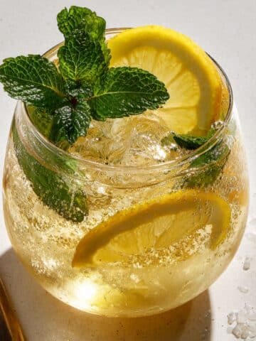 Limoncello spritz cocktail with crushed ice, lemon slices, and fresh mint in a wine glass.