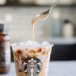 Cream swirling into iced coffee in a Starbucks cup with vanilla syrup nearby. Step-by-step copycat method in action.