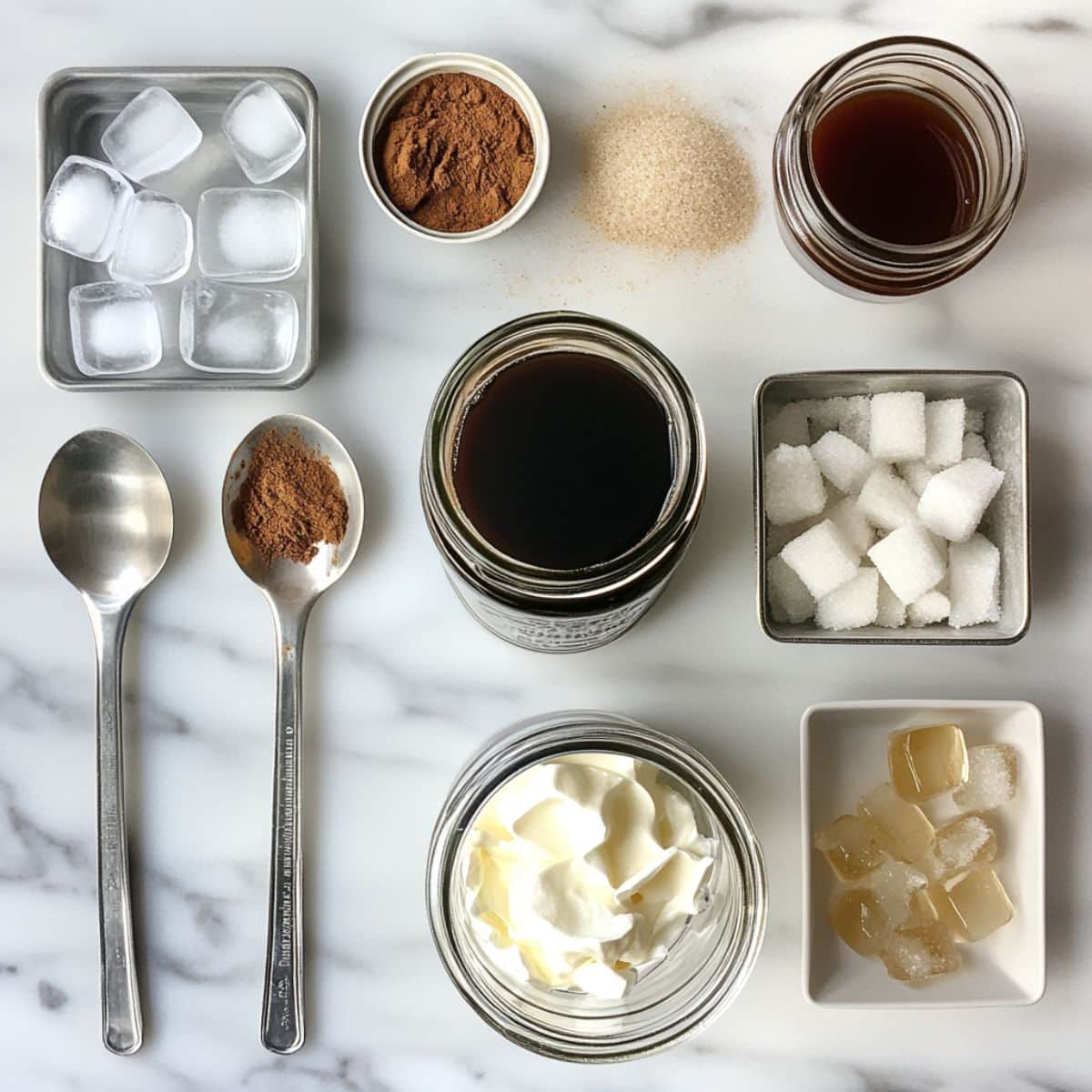 Overhead view of cold brew, cream, vanilla syrup, cinnamon, and other starbucks iced coffee ingredients on a kitchen counter.
