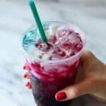 Homemade Summer Berry Refresher Starbucks copycat with ombré magenta-to-blue layers, ice cubes, and teal straw on white marble.