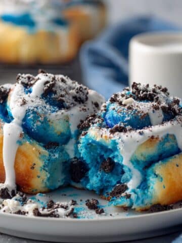 Homemade Cookie Monster cinnamon rolls with bright blue dough, white glaze, and cookie crumbles. Fun Sesame Street themed breakfast treats with vibrant blue swirls and cream cheese frosting.