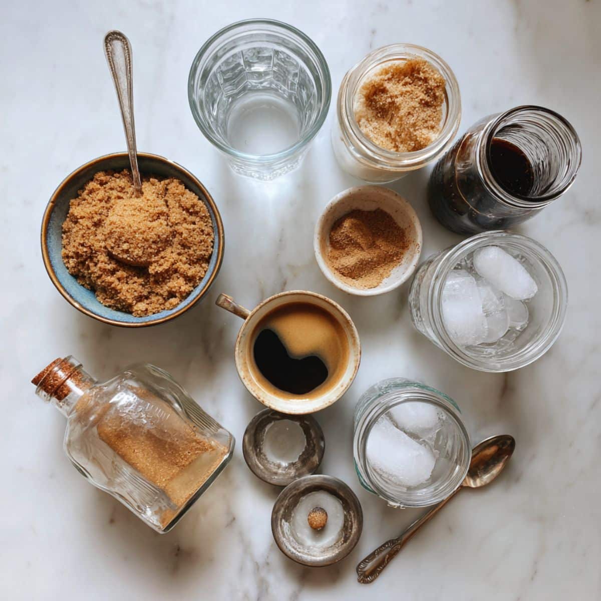 Overhead view of all brown sugar shaken espresso ingredients on a white counter. Includes oat milk, espresso, syrup items, and ice in a homemade setup.