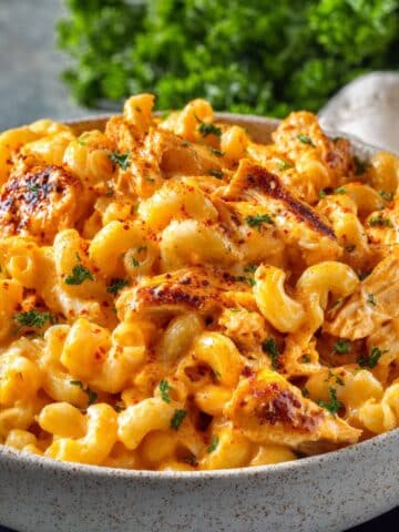 Buffalo chicken mac and cheese in ceramic bowl with creamy orange cheese sauce and fresh parsley garnish.