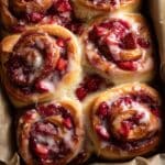 Homemade strawberry cinnamon rolls with glossy icing and fresh strawberry filling, close-up view of soft, fluffy dough swirled with jam and topped with a creamy glaze.
