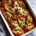 Golden bubbly stuffed shells with melted mozzarella and marinara sauce in baking dish on kitchen counter Homemade baked pasta shells filled with ricotta and meat topped with cheese perfect for Italian dinner