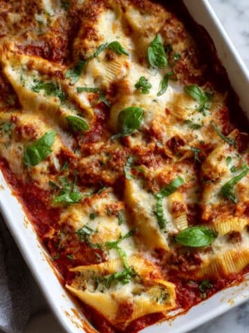 Golden bubbly stuffed shells with melted mozzarella and marinara sauce in baking dish on kitchen counter Homemade baked pasta shells filled with ricotta and meat topped with cheese perfect for Italian dinner
