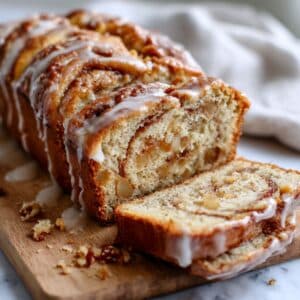 Cinnamon swirl apple fritter bread sliced showing golden interior with glaze and apple chunks with swirl pattern.