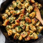 Golden garlic butter chicken bites in cast iron skillet with fresh parsley and melted butter.