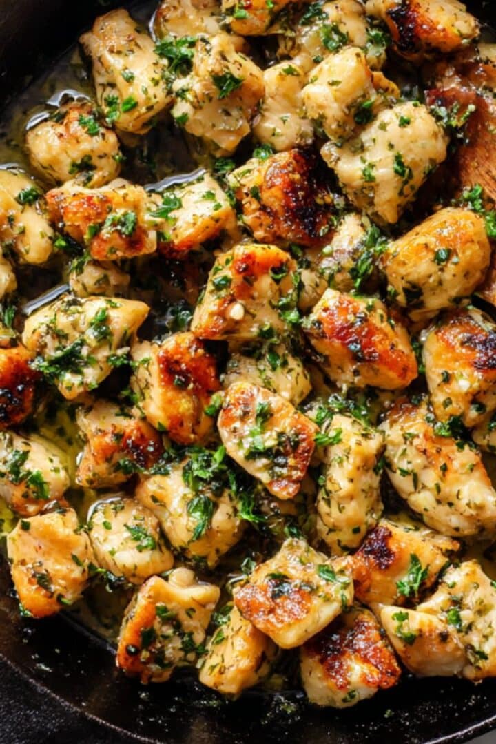 Golden garlic butter chicken bites in cast iron skillet with fresh parsley and melted butter.