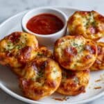 Crispy bagel bites air fryer with melted cheese and pepperoni on blue plate with marinara dipping sauce.
