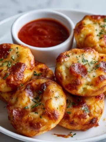 Crispy bagel bites air fryer with melted cheese and pepperoni on blue plate with marinara dipping sauce.
