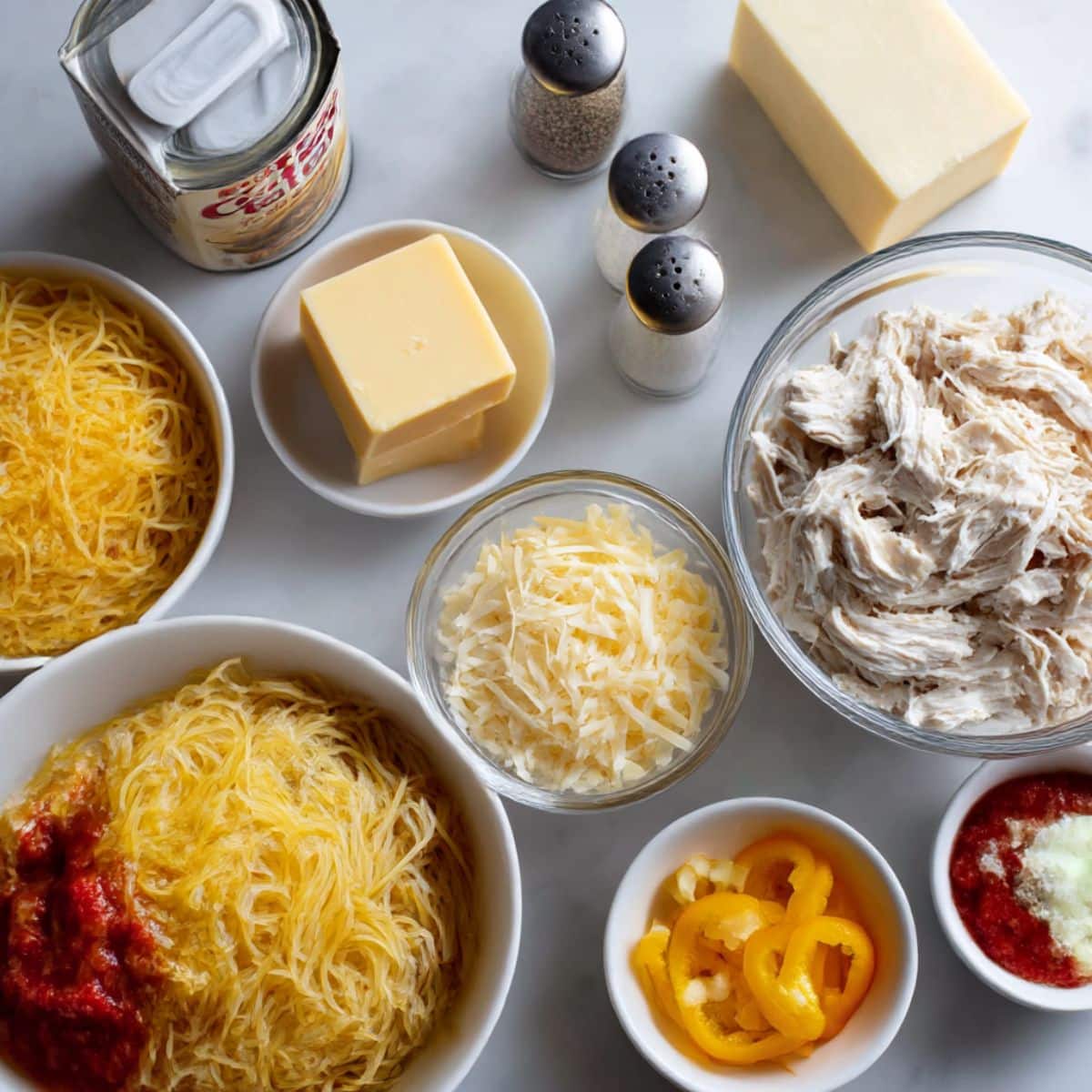 Complete ingredients for chicken spaghetti casserole recipe including pasta, rotisserie chicken, and cream cheese Essential chicken pasta casserole ingredients arranged on kitchen counter for easy homemade cooking
