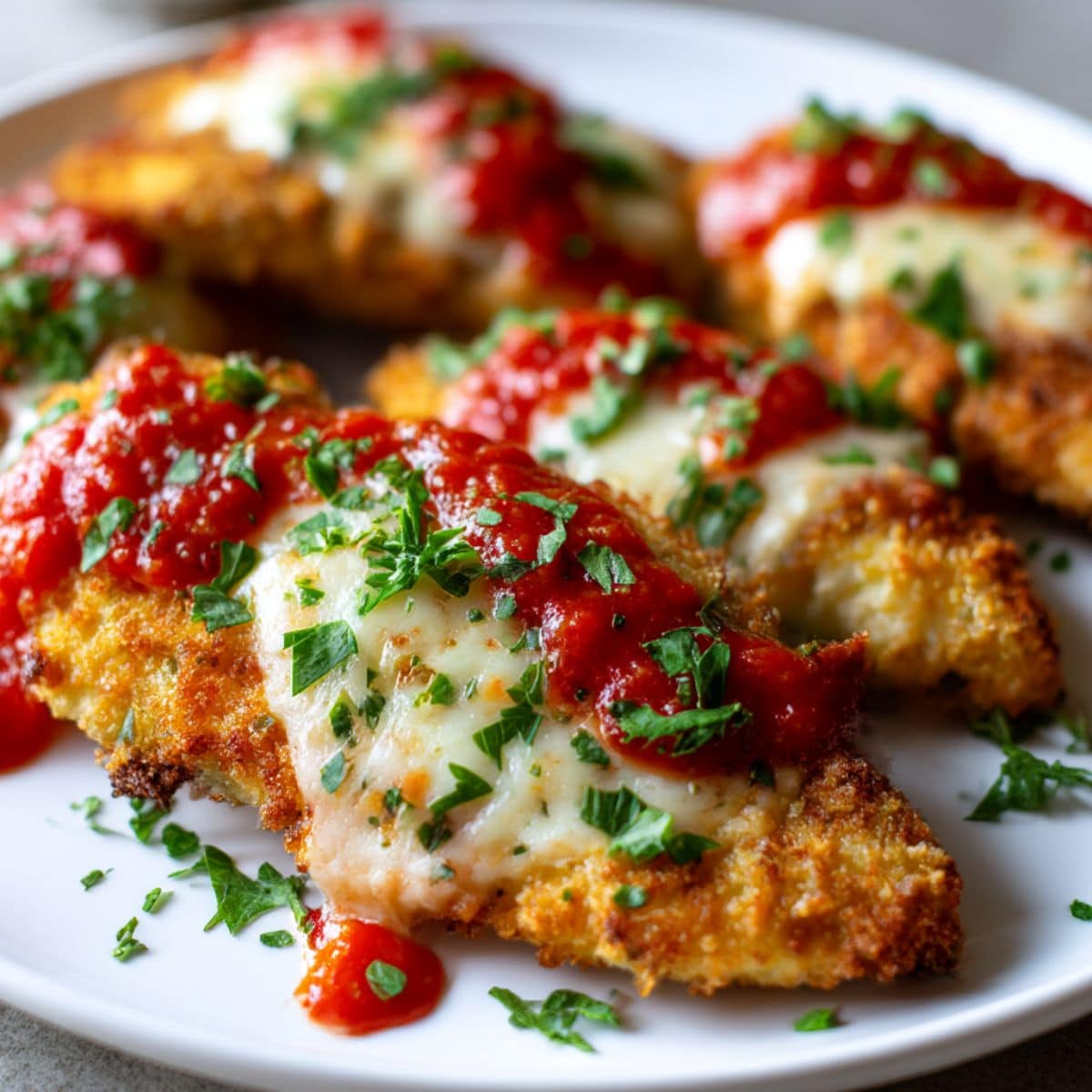 Crispy air fryer chicken parmesan topped with marinara, melted cheese, and fresh parsley.