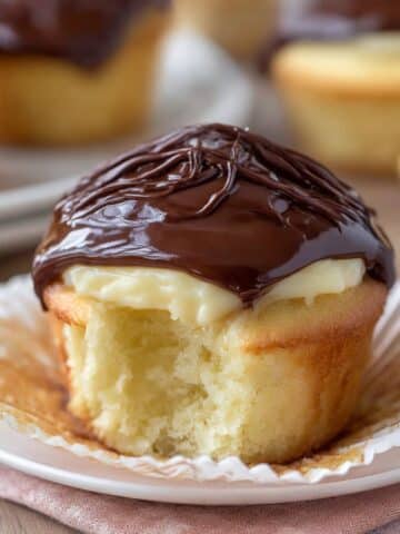 Boston cream pie cupcake filled with vanilla custard and topped with glossy chocolate ganache.