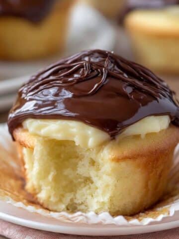 Boston cream pie cupcakes filled with vanilla custard and topped with glossy chocolate ganache.