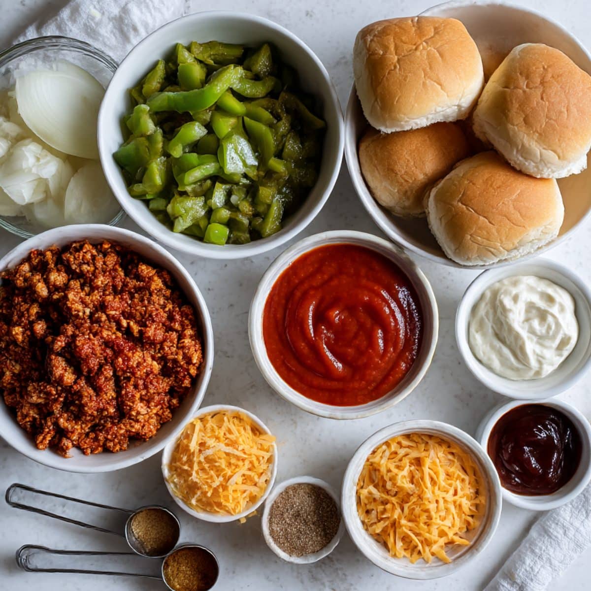 Overhead view of Cajun chicken sloppy joes ingredients including ground chicken, peppers, and spices.
