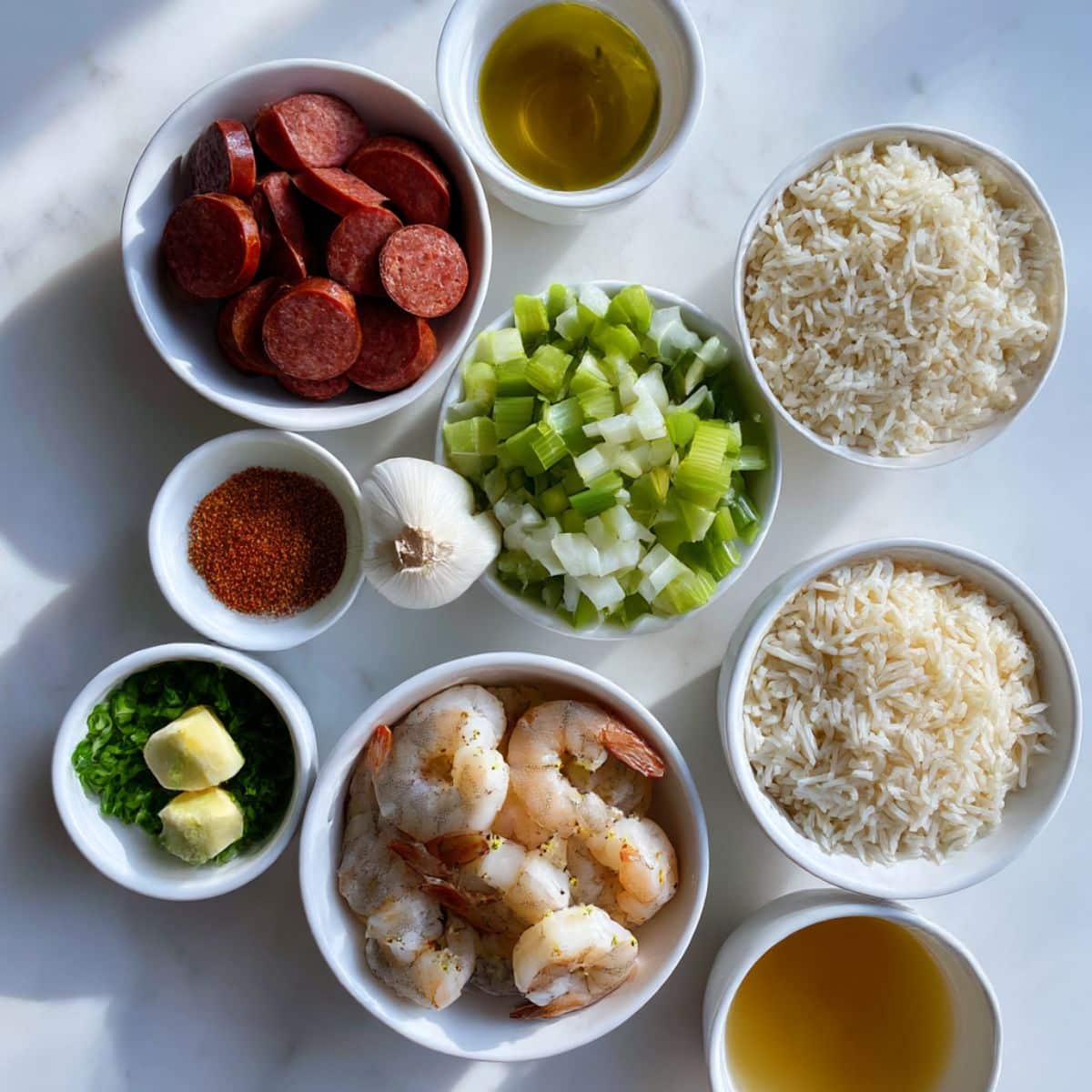 Overhead photo of sausage, shrimp, rice, vegetables, Cajun seasoning, and broth ingredients for dirty rice with sausage and shrimp.