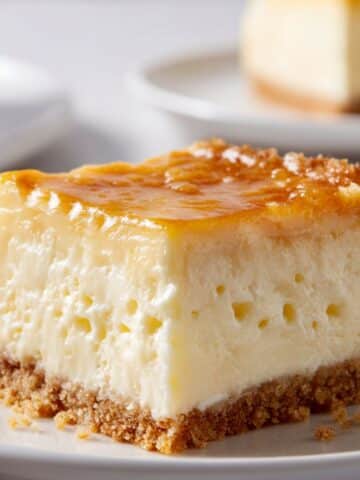 Golden gooey Neiman Marcus cake square with buttery crust and creamy center on a white plate.