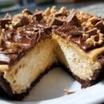 Whole peanut butter pie with chocolate topping and peanut garnish, sliced to show fluffy filling