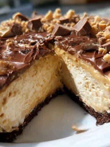 Whole peanut butter pie with chocolate topping and peanut garnish, sliced to show fluffy filling
