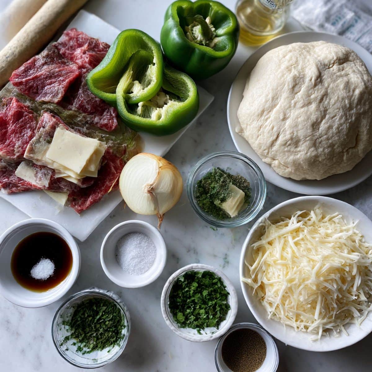 Overhead view of philly cheesesteak breadsticks ingredients including steak, peppers, onions, cheese, and dough.