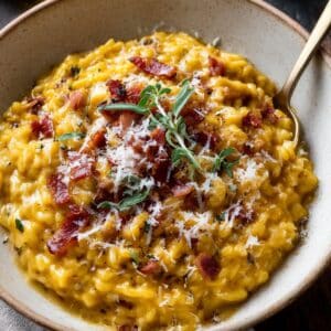 Creamy homemade pumpkin risotto topped with crispy bacon, Parmesan, and fresh sage