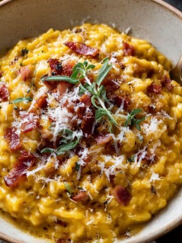 Creamy homemade pumpkin risotto topped with crispy bacon, Parmesan, and fresh sage