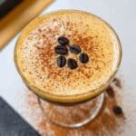 Pumpkin spice espresso martini topped with creamy foam, cinnamon dusting, and coffee beans.