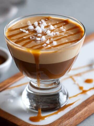 Salted caramel espresso martini with creamy foam, caramel drizzle, and sea salt flakes on top.
