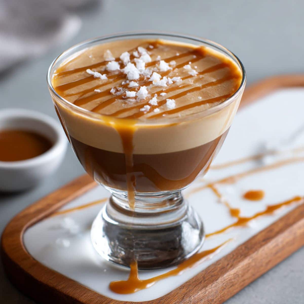Salted caramel espresso martini with creamy foam, caramel drizzle, and sea salt flakes on top.
