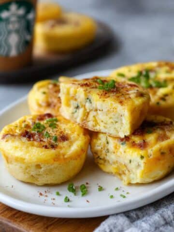 Fluffy copycat Starbucks egg bites with bacon and Gruyere cheese stacked on white plate, easy homemade high protein breakfast recipe
