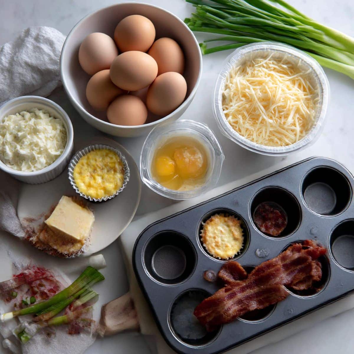 All ingredients for copycat Starbucks egg bites including eggs, cottage cheese, Gruyere cheese and bacon laid out ready for easy breakfast meal prep