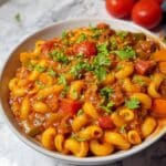 Homemade vegetarian goulash with elbow macaroni, bell peppers, and mushrooms in a smoky paprika tomato sauce, topped with fresh parsley.