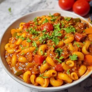 Homemade vegetarian goulash with elbow macaroni, bell peppers, and mushrooms in a smoky paprika tomato sauce, topped with fresh parsley.