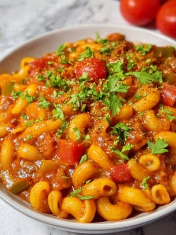 Homemade vegetarian goulash with elbow macaroni, bell peppers, and mushrooms in a smoky paprika tomato sauce, topped with fresh parsley.