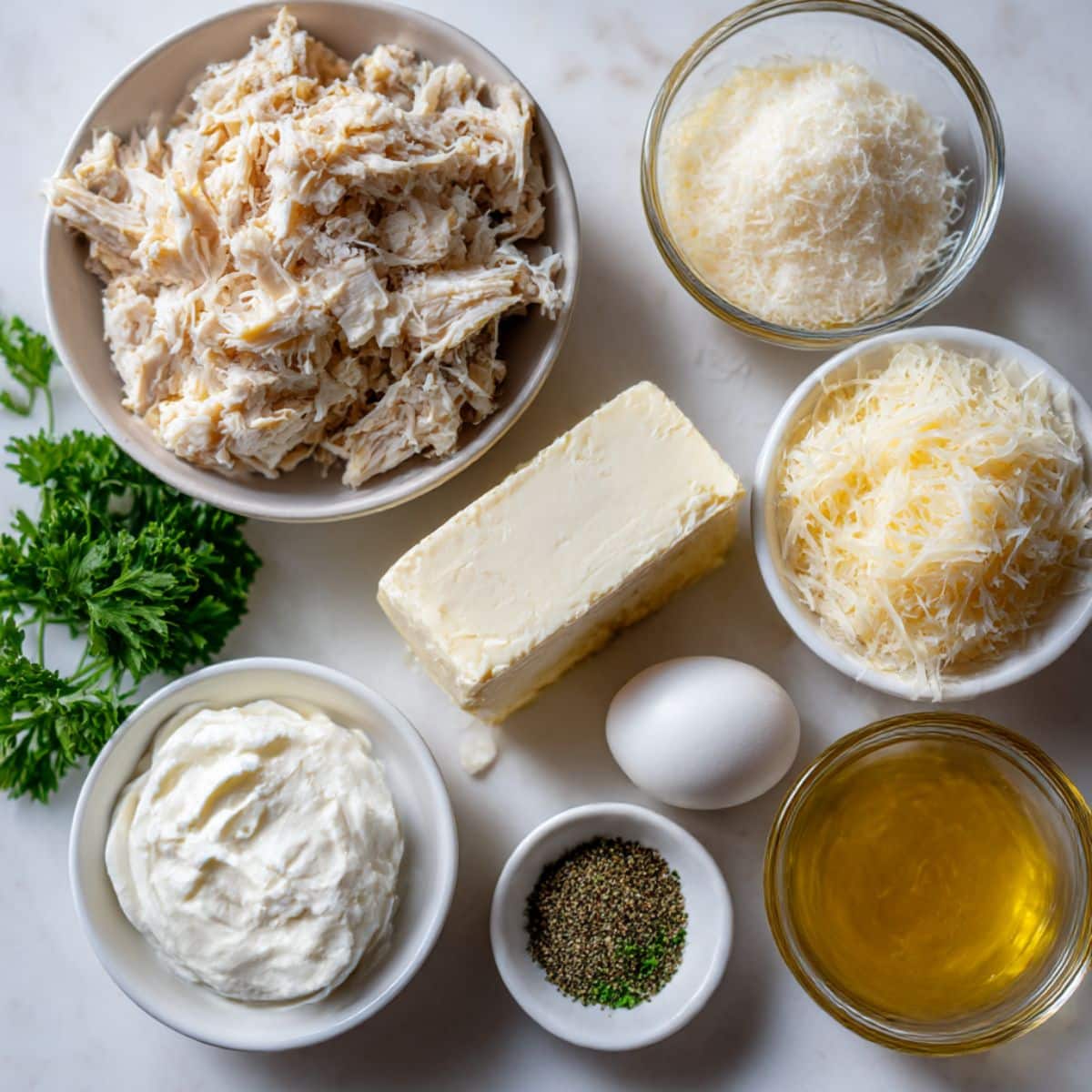 Overhead photo of ingredients for chicken pillows, including shredded chicken, cream cheese, crescent dough, and Parmesan.