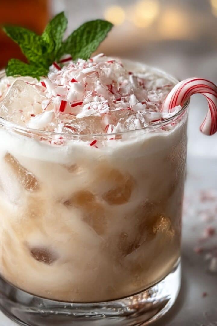 Peppermint white russian topped with crushed candy canes and ice, garnished with a mini candy cane and fresh mint.