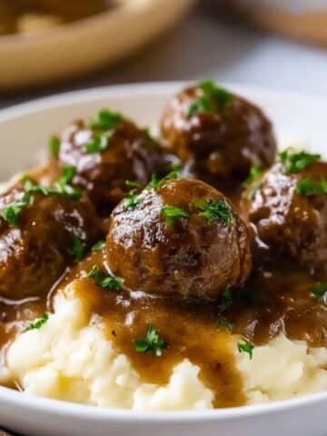 Homemade Salisbury steak meatballs served over creamy mashed potatoes with rich brown gravy.