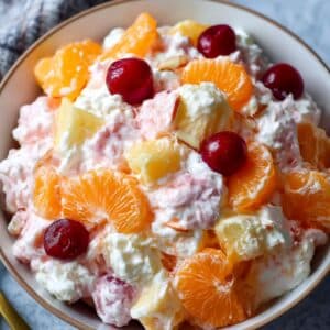 Ambrosia fruit salad with mandarin oranges, pineapple chunks, cherries, coconut, and marshmallows in a creamy dressing.