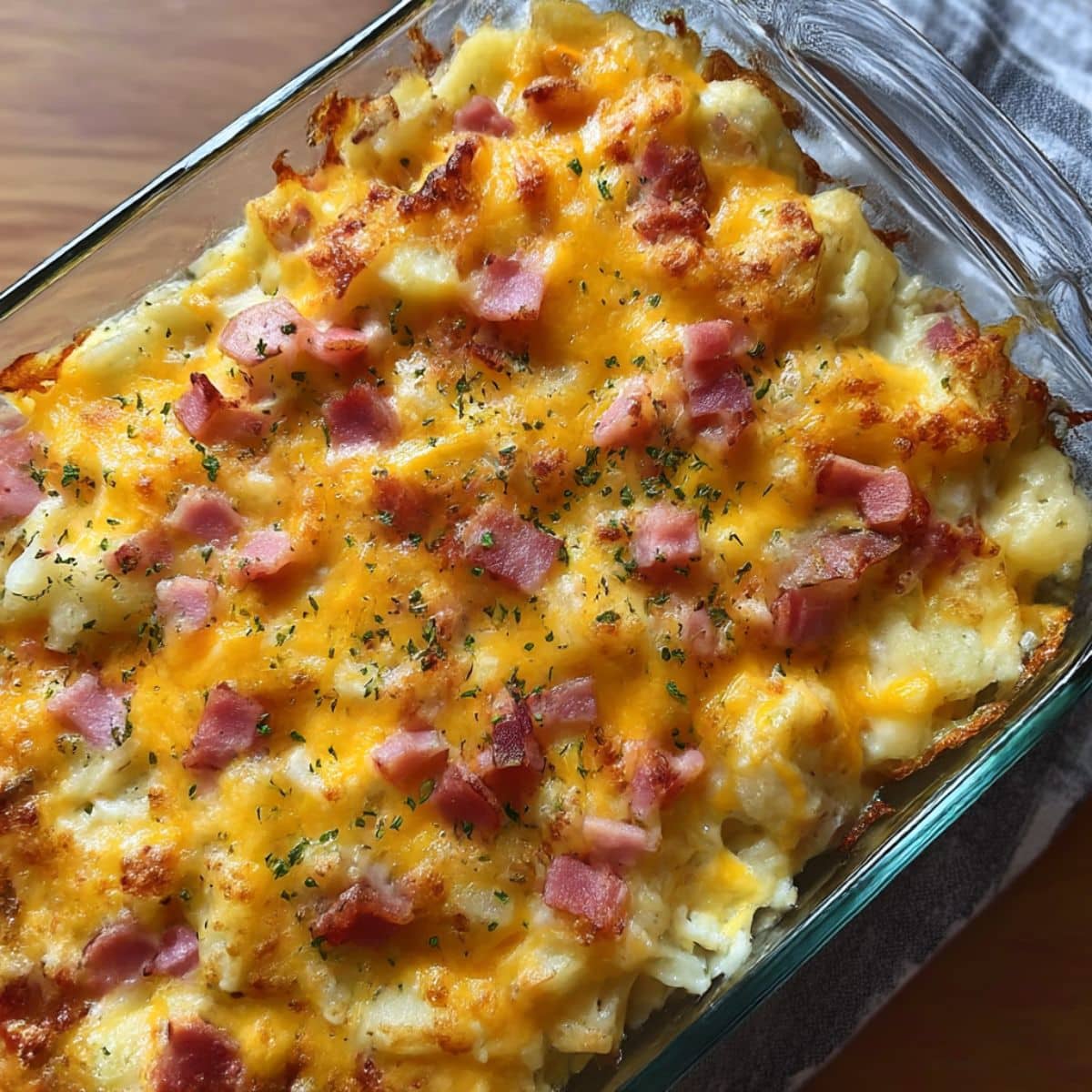 Golden baked cheesy ham potato casserole topped with melted cheddar and diced ham.