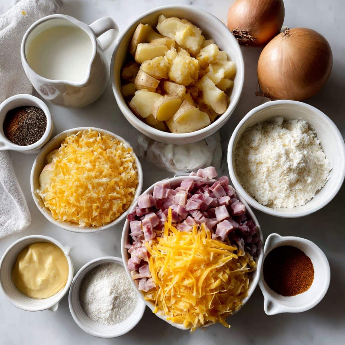 Ingredients for cheesy ham potato casserole including potatoes, ham, cheese, and homemade sauce components.