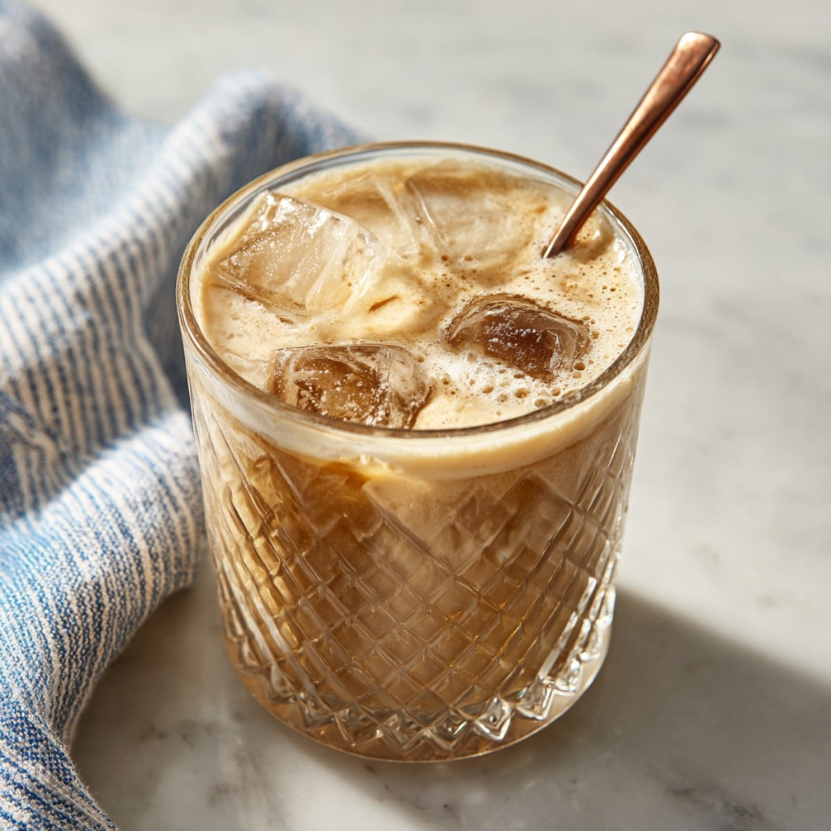 Creamy Root Beer Rum Cocktail served over ice in a cut-glass rocks tumbler with a creamy foam top.