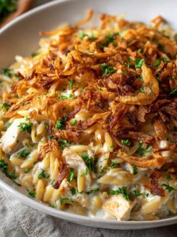 French onion chicken orzo casserole topped with crispy fried onions and fresh herbs
