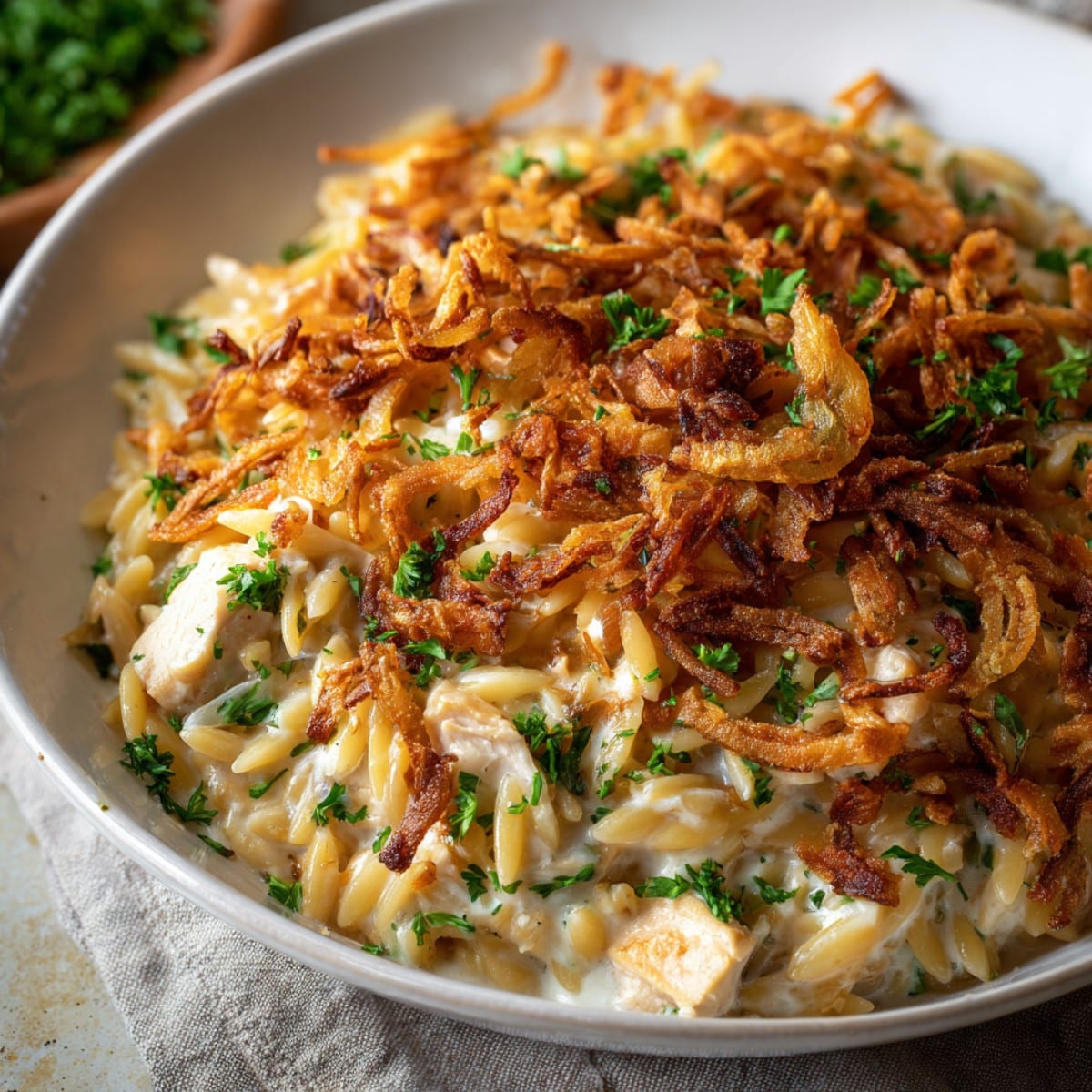 French onion chicken orzo casserole topped with crispy fried onions and fresh herbs