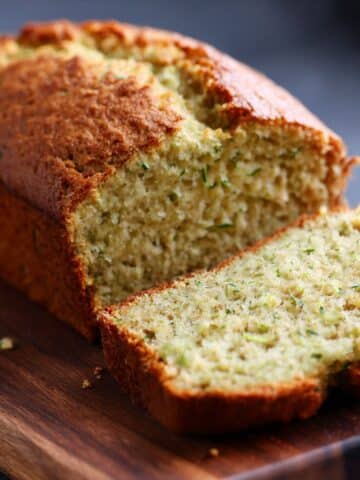Moist gluten free zucchini bread loaf baked golden, sliced to show a soft, tender crumb with fresh zucchini throughout