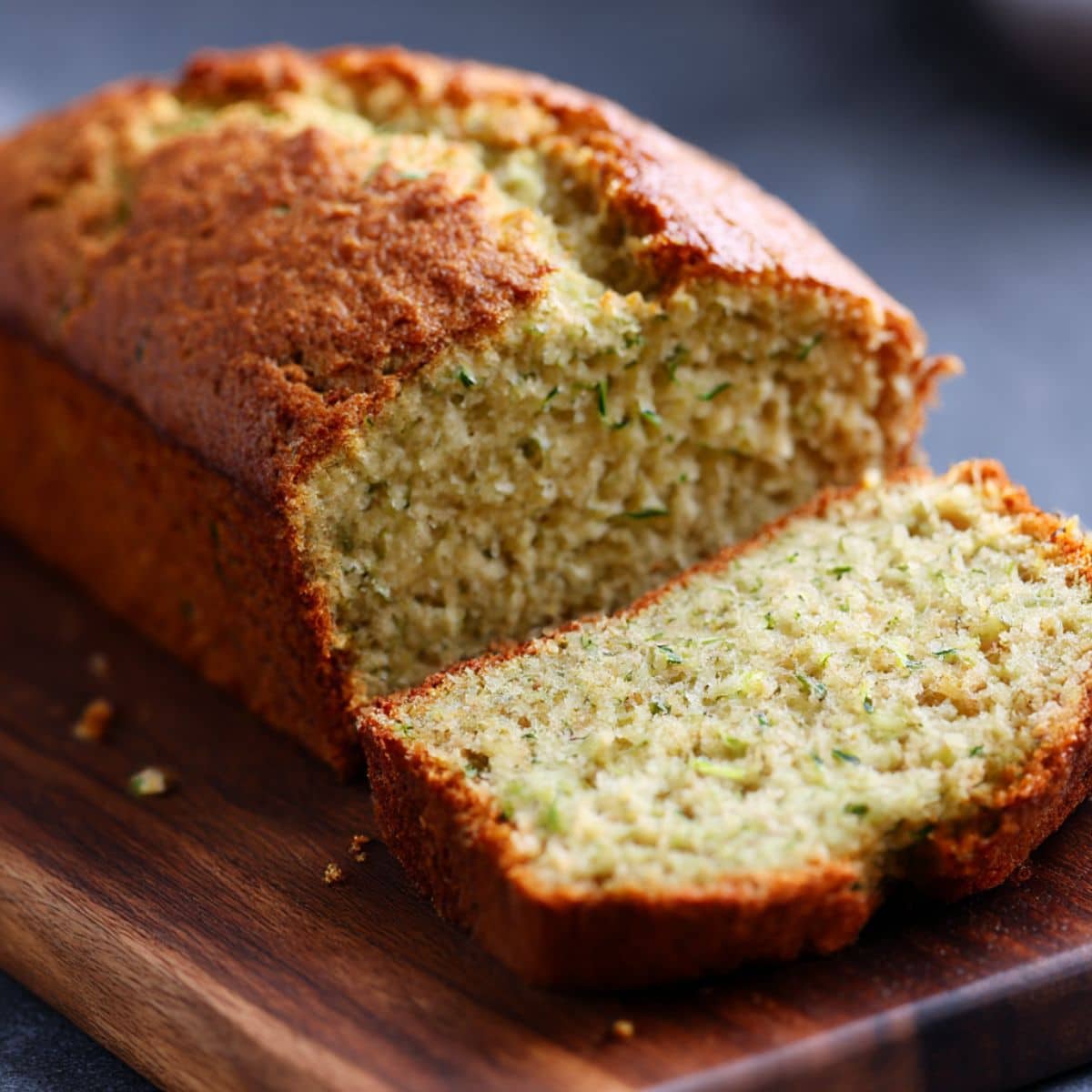 Moist gluten free zucchini bread loaf baked golden, sliced to show a soft, tender crumb with fresh zucchini throughout