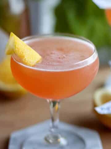 Paper Plane Cocktail in a coupe glass with a lemon twist garnish.